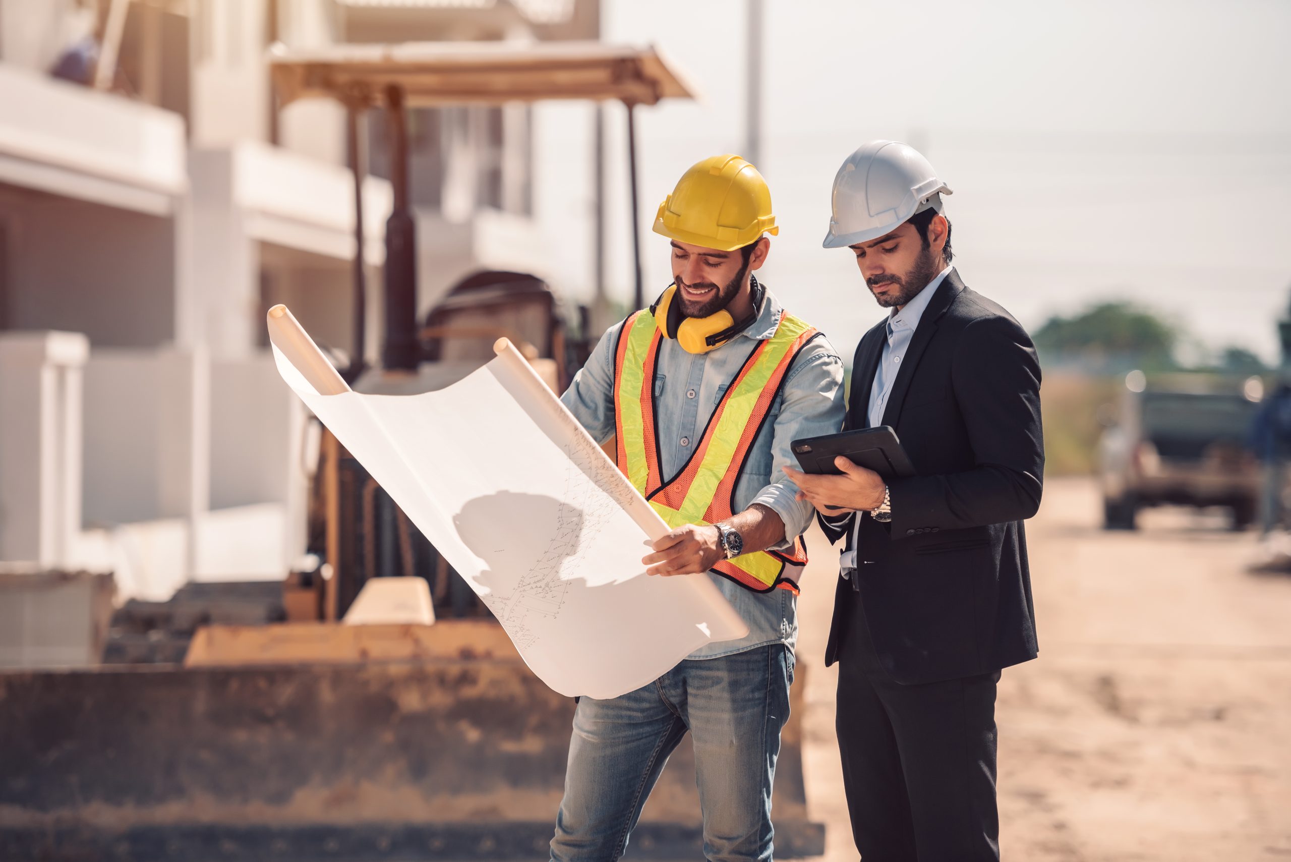 Civil engineer and construction worker manager holding digital tablet and blueprints , talking and planing about construction site. Cooperation teamwork concept.